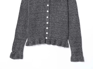 Detail of dark grey knit cardigan featuring white buttons and ruffled lettuce edge hem