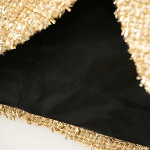Detailed close-up of golden tweed fabric texture with luxury metallic woven finish