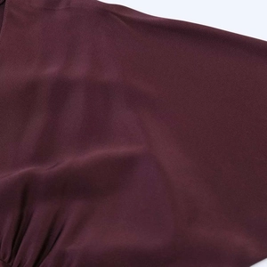 Détail de la robe foulard en satin bordeaux montrant la texture fluide et la couture