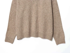 Gros plan sur les poignets côtelés et la texture du bas de ce pull en maille marron