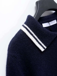 Detail view of navy blue knit polo neck with white stripe and brand size label