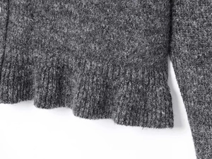 Detail of dark grey knit cardigan showing soft wool texture and ribbed hem craftsmanship