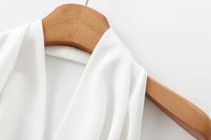 Detail shot of halter neck white crepe jumpsuit neckline on wooden hanger