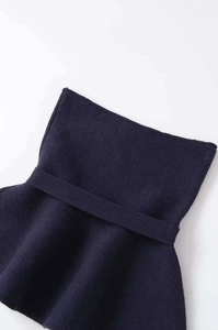 Detailed close-up of navy blue knit fabric with ruffle hem and elastic waistband texture