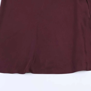 Gros plan détaillé de l'ourlet en satin bordeaux avec coutures fines et texture en soie