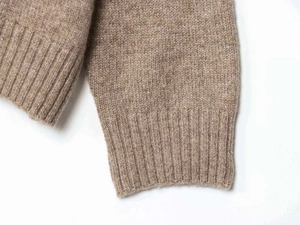Détail du tricot chiné marron clair avec poignets côtelés et texture douce