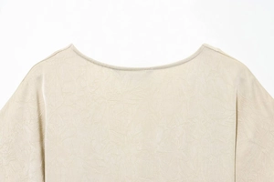 Close-up of the neckline and crinkled satin texture on the beige midi dress