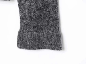 Detailed close-up of dark grey knitted fabric showing premium ribbed cuffs and wool texture