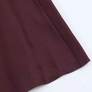 Gros plan détaillé montrant la texture satinée lisse et l'ourlet soigné de la robe bordeaux