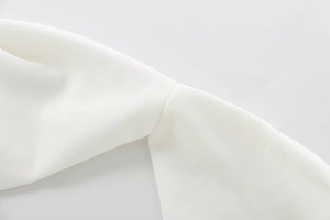 Close-up of white crepe fabric texture and neat stitching on a halter jumpsuit