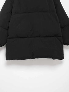 Detail view of black quilted puffer jacket showing horizontal stitching and matte fabric