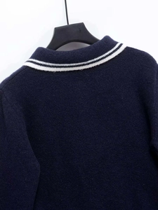 Detailed view of dark blue knit top featuring a white striped polo collar texture
