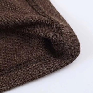 Détail du tissu en maille marron montrant la précision de la couture à double aiguille