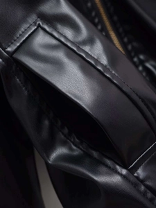 Detailed macro shot of premium black faux leather jacket with precision stitching and pocket detail