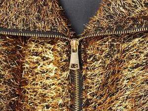 Close-up of golden fringe fabric texture with high-quality metal zipper on jacket