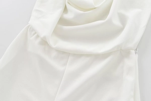 Detail shot of white crepe jumpsuit featuring elegant pleats and a hidden side zipper