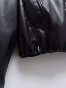 Detailed close-up of faux leather jacket hem with elasticated waist and stitched pocket