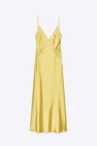Detailed view of yellow satin dress featuring delicate lace trim and V-neckline texture