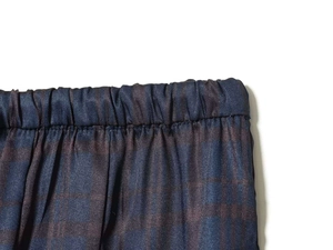 Detail of elastic waist and dark blue plaid textured fabric on these loose trousers