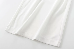 Close-up of white crepe fabric texture and double-needle hem detail on halter jumpsuit