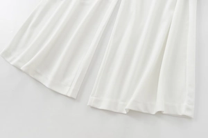 Detail view of the hem stitching and smooth white fabric on wide-leg trousers