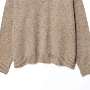 Pull en maille marron avec col en V, ourlet côtelé et texture cachemire douce sur blanc