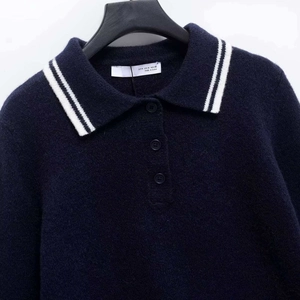 Navy blue knit polo sweater with white striped collar and button detail on white background