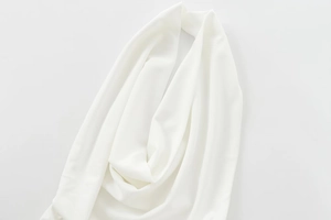 Detailed view of white crepe fabric featuring a halter neck design and soft elegant drapes
