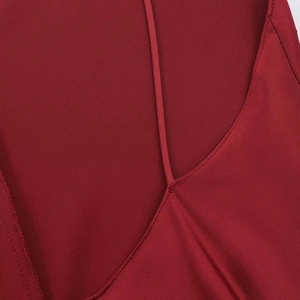 Detail view of the fine spaghetti straps and V-neckline on a silky dark red satin midi dress