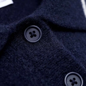 Detail of dark blue knit sweater showing matte four-hole buttons and wool texture