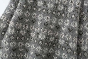 Close-up of grey jacquard knit sweater with fuzzy floral and geometric patterns