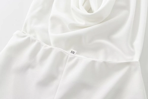 Close-up of white crepe halter neck jumpsuit with cowl neckline and size label