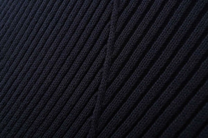 Macro detail of the dark blue ribbed knit fabric texture showing vertical patterns