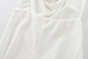Detail of white crepe fabric with soft draping and XS size label on the waistline