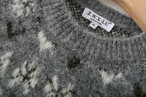 Close-up of crew neck collar with brand label on grey and white jacquard knit sweater