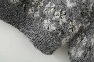 Detail of grey Fair Isle jacquard knit sweater showing fuzzy mohair texture and ribbed cuffs