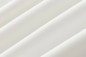 Macro shot of pure white crepe fabric texture and pleated details on a halter jumpsuit
