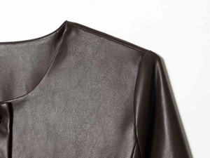 Macro detail of dark brown faux leather jacket showing lychee grain texture and stitching