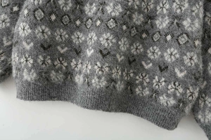 Close-up of grey mohair knit sweater featuring snowflake jacquard and ribbed hem detail