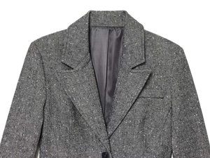 Detailed view of grey herringbone blazer showing notch lapels and textured wool tweed fabric