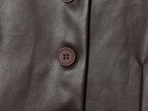 Macro shot of dark brown PU leather texture and button detailing on the vintage jacket
