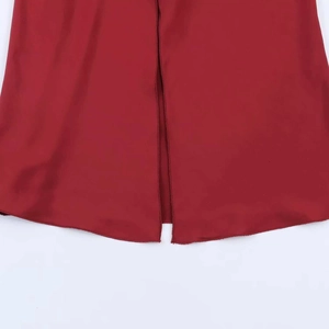Detail of red satin dress hem featuring a clean central slit and smooth fabric texture