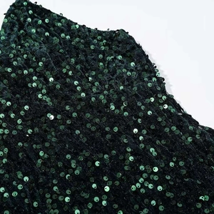 Close-up of deep green sequin fabric showing shimmering metallic luster and texture