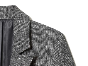 Detail of grey herringbone wool blazer showing premium fabric texture and inner lining