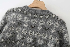 Detailed view of the crew neck collar on a grey jacquard knitted sweater with snowflake pattern