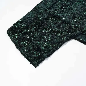Macro detail of dark green sequins on black mesh fabric with metallic reflection