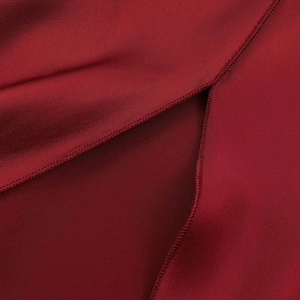 Detailed view of the split hem and neat stitching on a burgundy satin midi dress