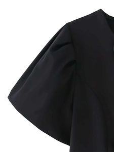 Détail de la manche bouffante noire élégante avec plis à l'épaule sur mini robe