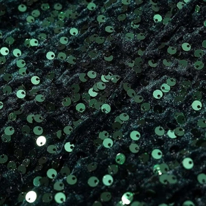 Close-up of deep green sequins on velvet fabric showing metallic texture and detail