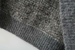 Detailed close-up of charcoal and brown houndstooth jacquard knit with ribbed hem